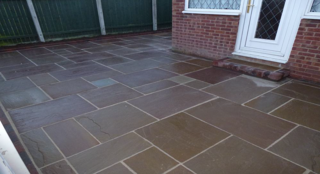 Riven sandstone patio in plum and grey tones beside a house door