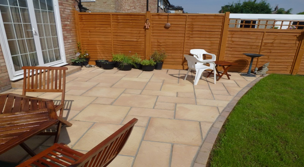 Buff sandstone patio with charcoal edging and garden furniture